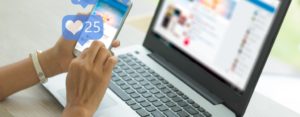 a pair of hands using social media on her phone and laptop